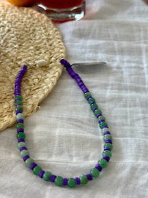 Necklace with purple and green beads on a light surface